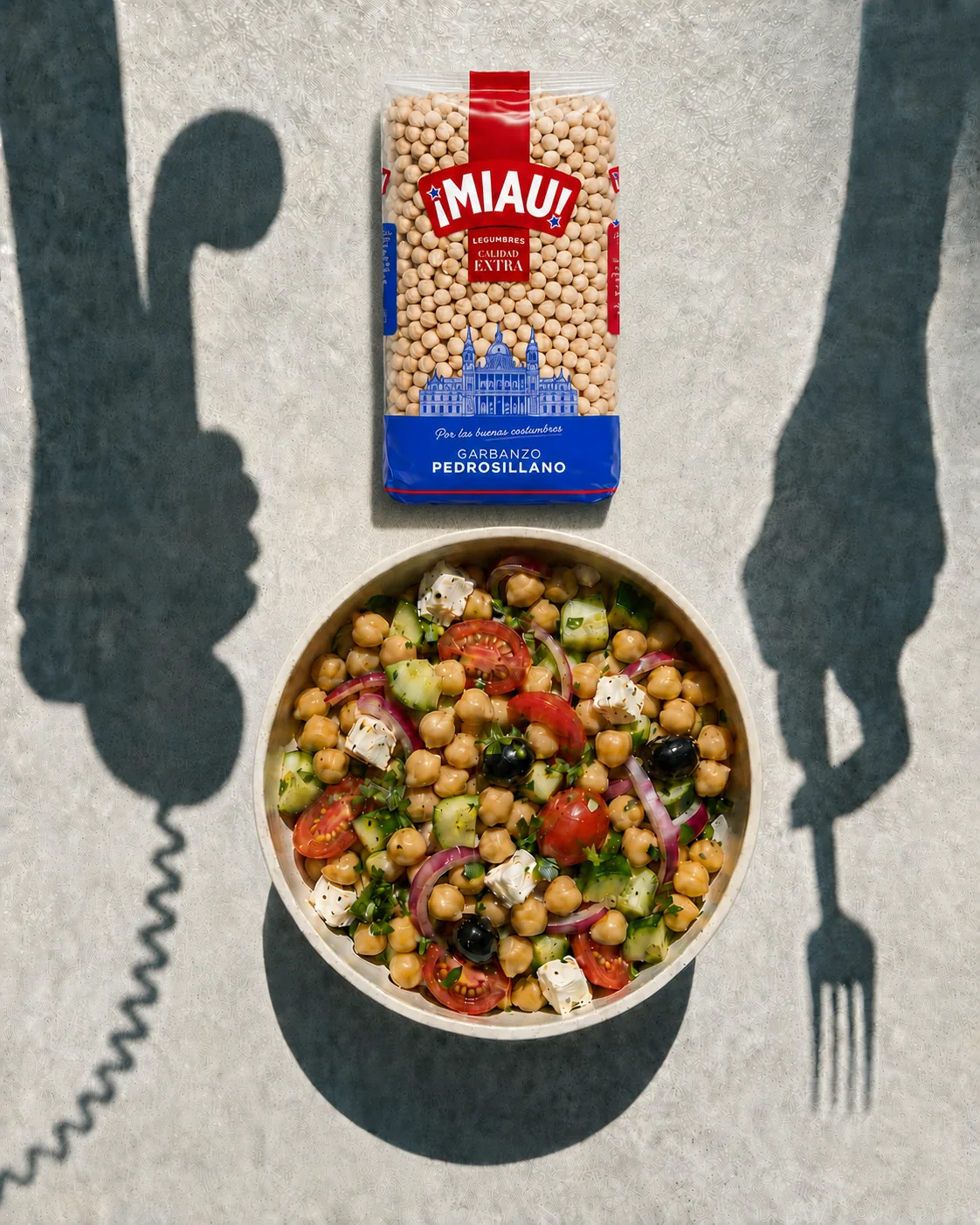 Paquete de Garbanzo Pedrosillano MIAU junto a un bol de ensalada de garbanzos, con las sombras de un telefono y un tenedor